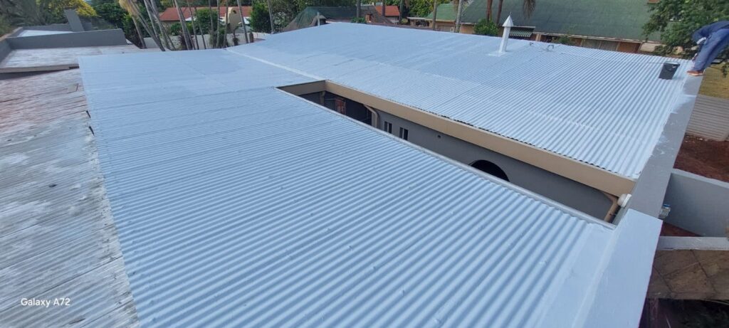 Corrugated house roof being waterproofed